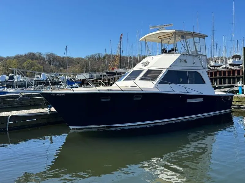 Slide: The Image of 1985 Egg Harbor 37 Convertible yacht docked at a marina, under clear blue skies. - 1
