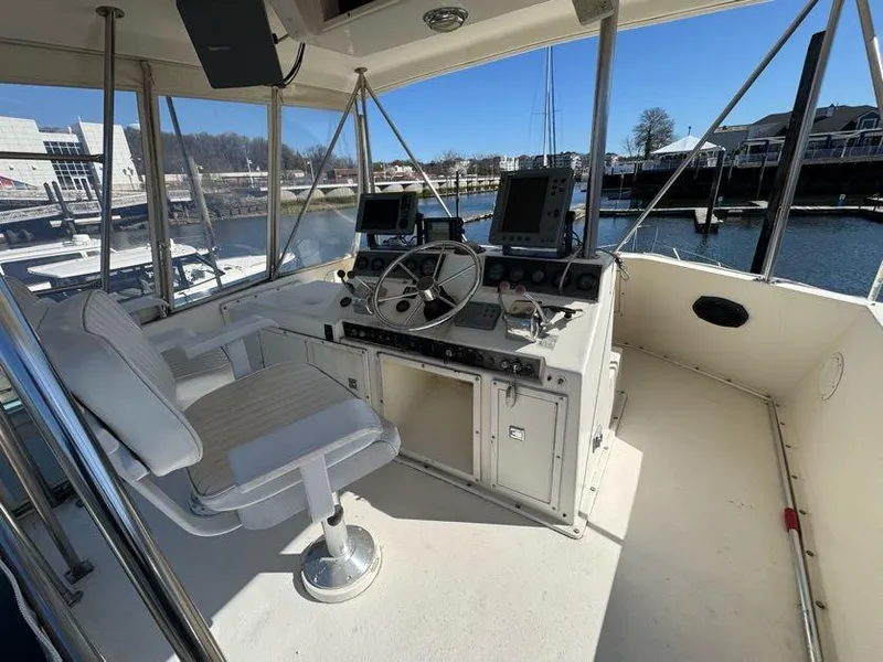 Slide: The Image of 1985 Egg Harbor 37 Convertible helm with steering wheel, controls, and navigation equipment in a marina. - 14