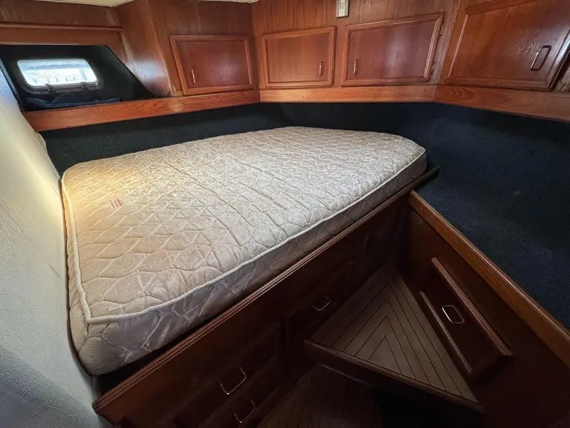 Slide: The Image of 1985 Egg Harbor 37 Convertible cabin with bed, wooden cabinets, and window. - 27