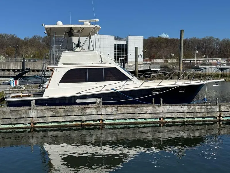 Slide: The Image of 1985 Egg Harbor 37 Convertible yacht docked at marina, reflecting on calm water. - 4