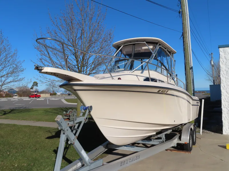 Slide: The Image of 2006 Grady-White Journey 258 boat on trailer, parked outdoors under clear blue sky. - 2