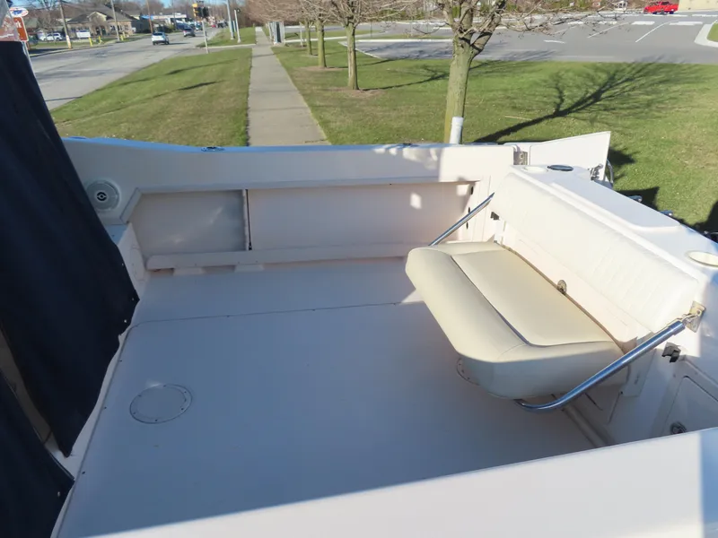 Slide: The Image of 2006 Grady-White Journey 258 boat deck with seating, parked near a grassy area. - 6