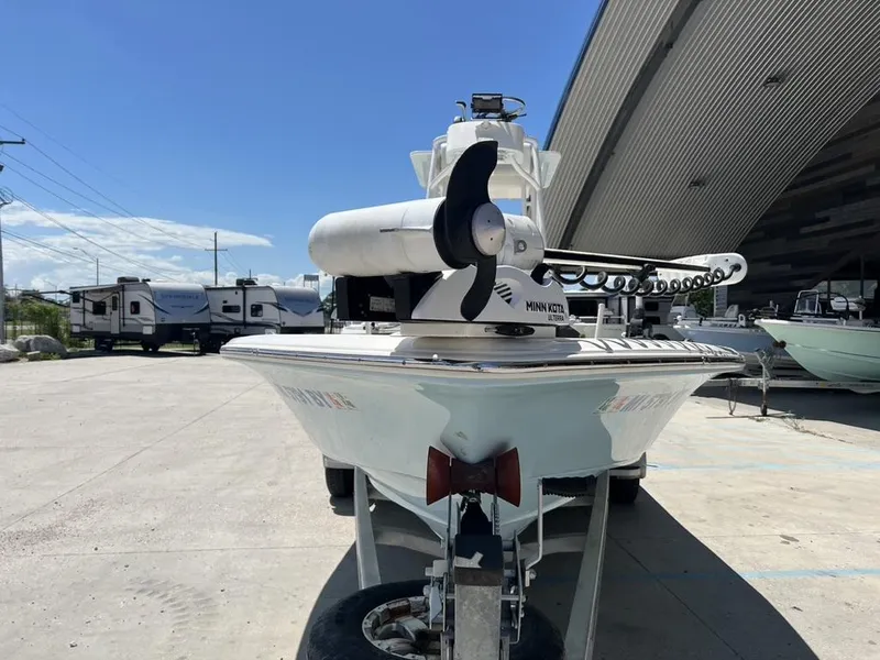 Slide: The Image of 2016 Avenger AV 26 boat with Minn Kota motor, parked near RVs and a large building. - 6