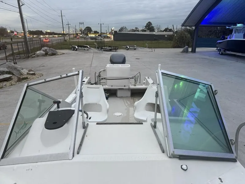 Slide: The Image of 1977 Boston Whaler 21 REVENGE boat, open deck view, parked outdoors. - 9