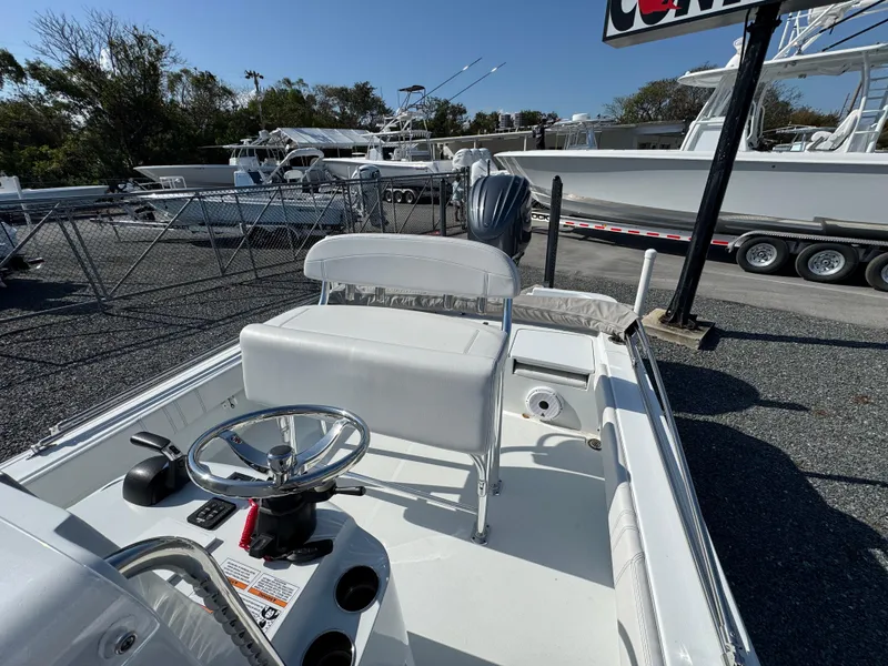 Slide: The Image of 2023 Contender 25 Bay boat interior with steering wheel and seating, displayed outdoors. - 10