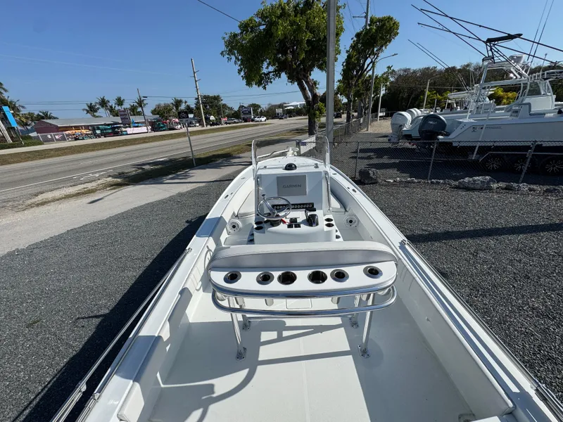 Slide: The Image of 2023 Contender 25 Bay boat with fishing rod holders, parked on gravel near a road. - 14