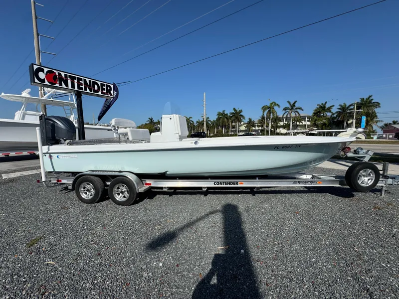 Slide: The Image of 2023 Contender 25 Bay boat on trailer, displayed outdoors under clear blue sky. - 3