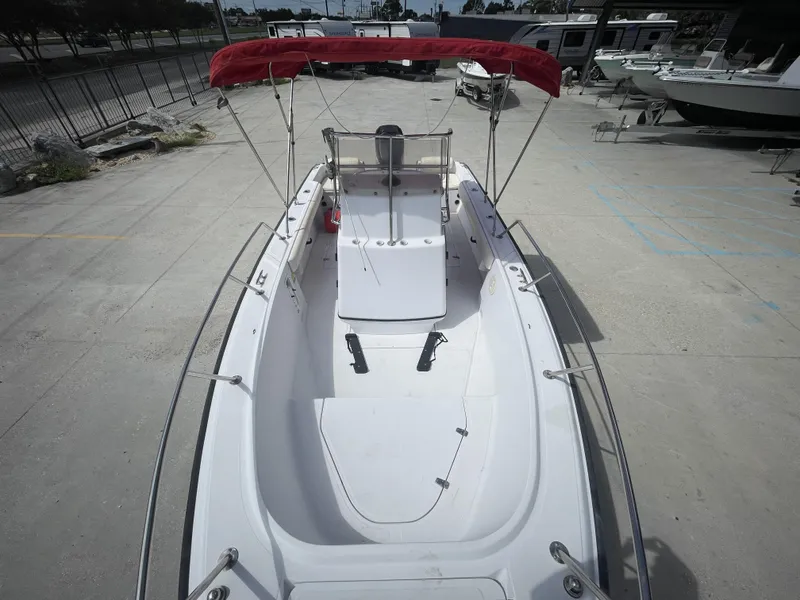 Slide: The Image of 1997 Boston Whaler 21 Outrage boat with red canopy, docked on concrete surface. - 23