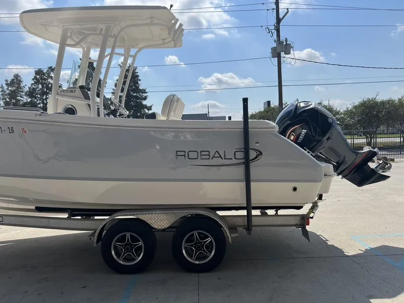 Slide: The Image of 2023 Robalo 230 boat on trailer with Yamaha outboard motor, parked outdoors. - 2