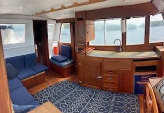 Slide: The Image of 1989 Grand Banks GND01 yacht interior with wooden cabinetry, blue seating, and nautical decor. - 11