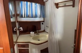 Slide: The Image of 1989 Grand Banks GND01 bathroom with sink, mirror, and blue-striped curtains. - 16