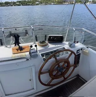 Slide: The Image of 1989 Grand Banks GND01 boat helm with wooden steering wheel, on calm water. - 22