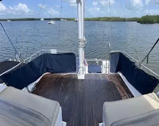 Slide: The Image of 1989 Grand Banks GND01 yacht deck with seating, overlooking serene waters and distant boats. - 23