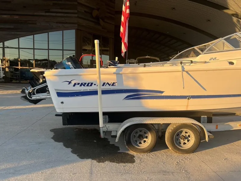 Slide: The Image of 2002 Pro-Line 22DC boat on trailer, parked outdoors with American flag. - 9