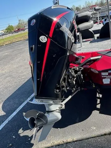 Slide: The Image of 2025 Tracker Savage 215 boat engine with sleek black and red design in a parking lot. - 2