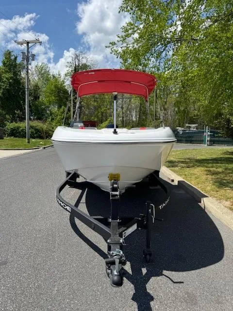 Slide: The Image of 2025 Tahoe T18 boat with red canopy on trailer, parked on sunny street. - 6