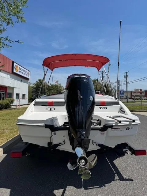 Slide: The Image of 2025 Tahoe T18 boat with red canopy and outboard motor, parked outdoors. - 7