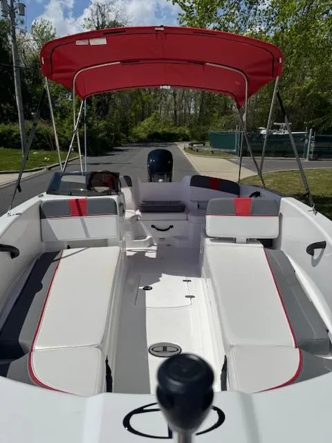 Slide: The Image of 2025 Tahoe T18 boat with red canopy, white and gray seating, parked outdoors. - 8