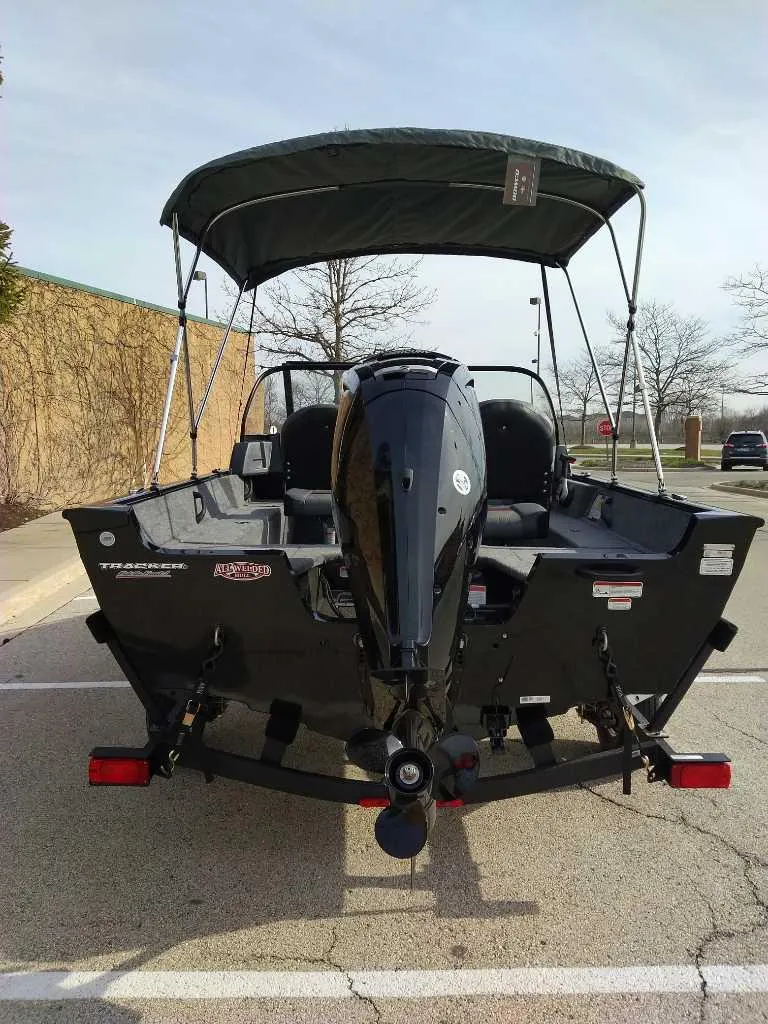 Slide: The Image of 2025 Tracker Pro Guide V-16 WT boat with canopy, parked outdoors. - 4