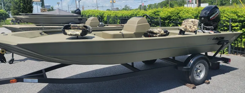 Slide: The Image of 2025 Tracker Grizzly 1754 SC boat on trailer, parked outdoors, with camouflage seats. - 4