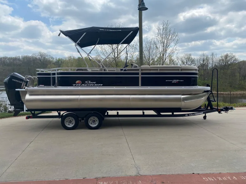The Image of 2025 Sun Tracker SportFish 22 XP3 pontoon boat on trailer, parked outdoors. - 0
