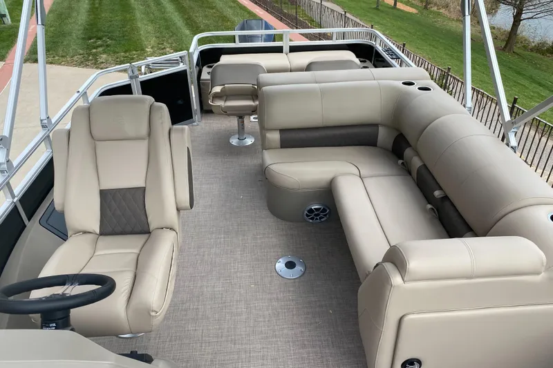Slide: The Image of 2025 Sun Tracker SportFish 22 XP3 pontoon boat interior with beige seating and steering wheel. - 4