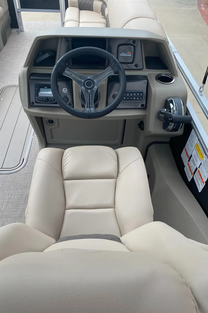Slide: The Image of 2025 Sun Tracker SportFish 22 XP3 boat interior with steering wheel and beige seating. - 6