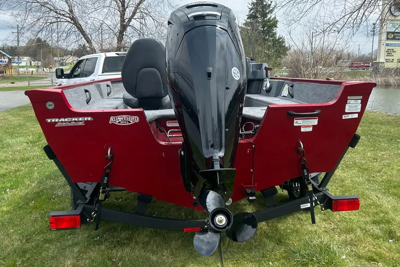 Slide: The Image of 2025 Tracker Pro Guide V-16 SC boat, red exterior, parked on grass. - 5