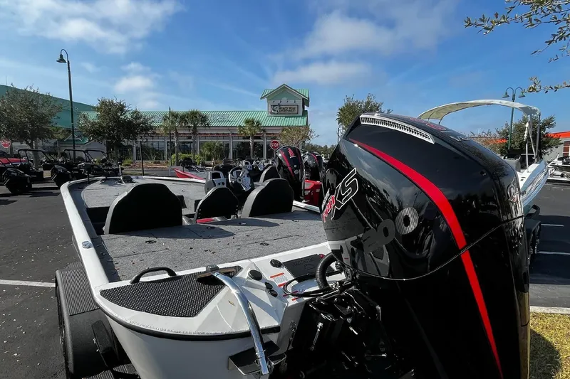 Slide: The Image of 2025 Tracker Savage 215 boat with powerful outboard motor in a sunny outdoor showroom. - 2