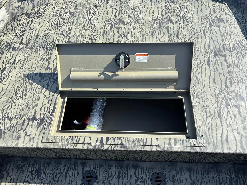 Slide: The Image of Open storage compartment on 2025 Tracker Grizzly 1860 CC boat, featuring camouflage pattern. - 12