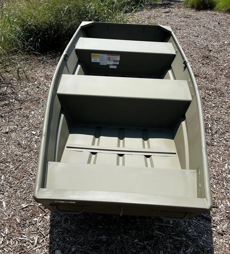 Slide: The Image of 2025 Tracker Grizzly 12 Jon boat on a grassy area, showcasing its sturdy design. - 2