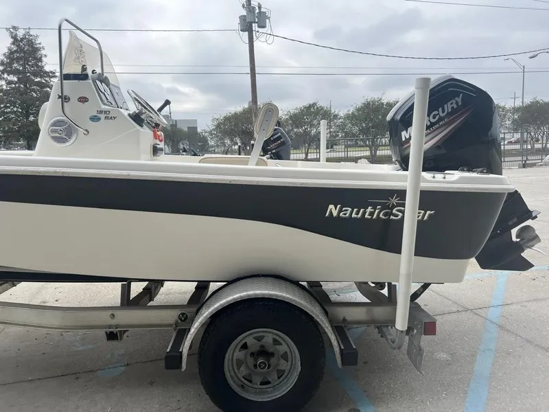 Slide: The Image of 2018 NauticStar 1810 Bay boat on trailer with Mercury engine, parked outdoors. - 9