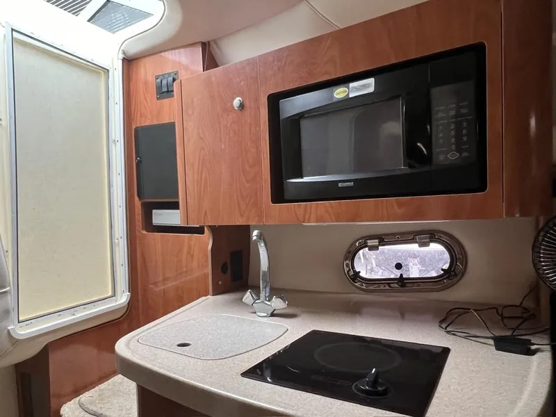 Slide: The Image of 2004 Four Winns 248 Vista boat kitchen with microwave, sink, and stove. - 18