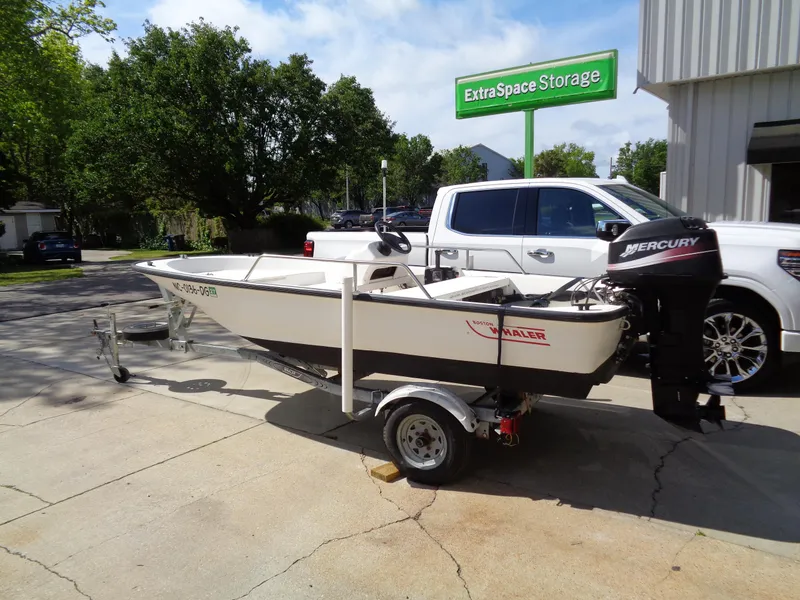 Slide: The Image of 2000 Boston Whaler 13 Sport boat on trailer, parked near Extra Space Storage facility. - 13
