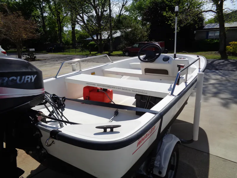 Slide: The Image of 2000 Boston Whaler 13 Sport boat with Mercury engine, parked on a driveway. - 4