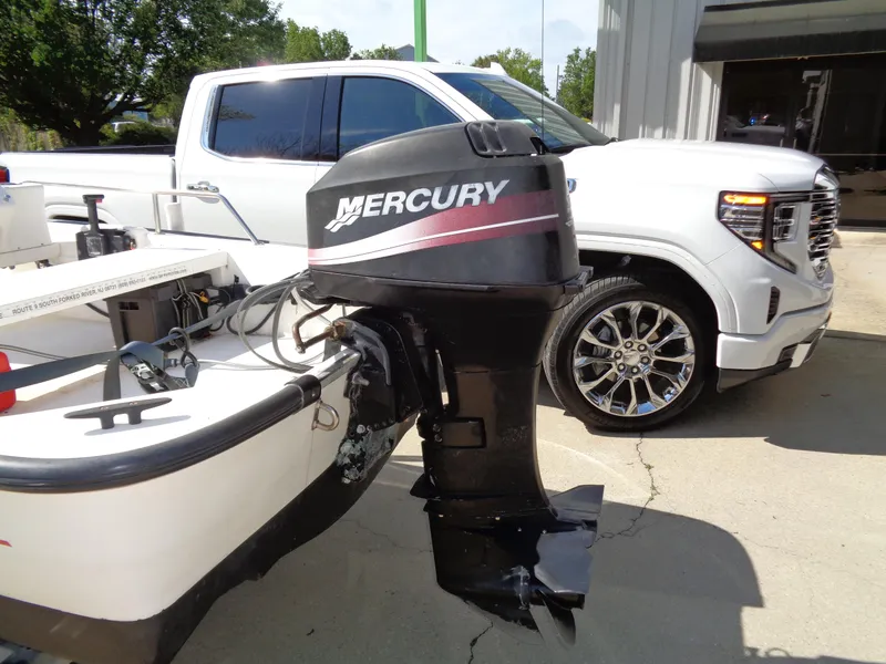 Slide: The Image of 2000 Boston Whaler 13 Sport boat with Mercury outboard motor, parked near a white truck. - 6