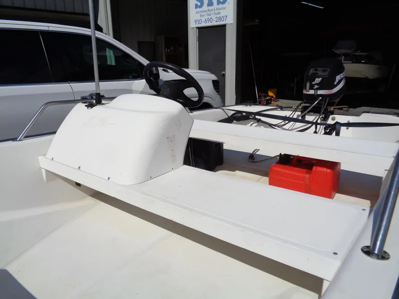Slide: The Image of 2000 Boston Whaler 13 Sport boat interior with steering wheel and motor, parked near a vehicle. - 8