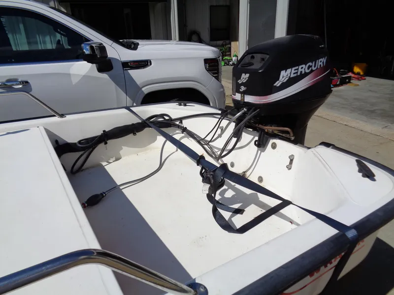 Slide: The Image of 2000 Boston Whaler 13 Sport boat with Mercury outboard motor, parked beside a white vehicle. - 9