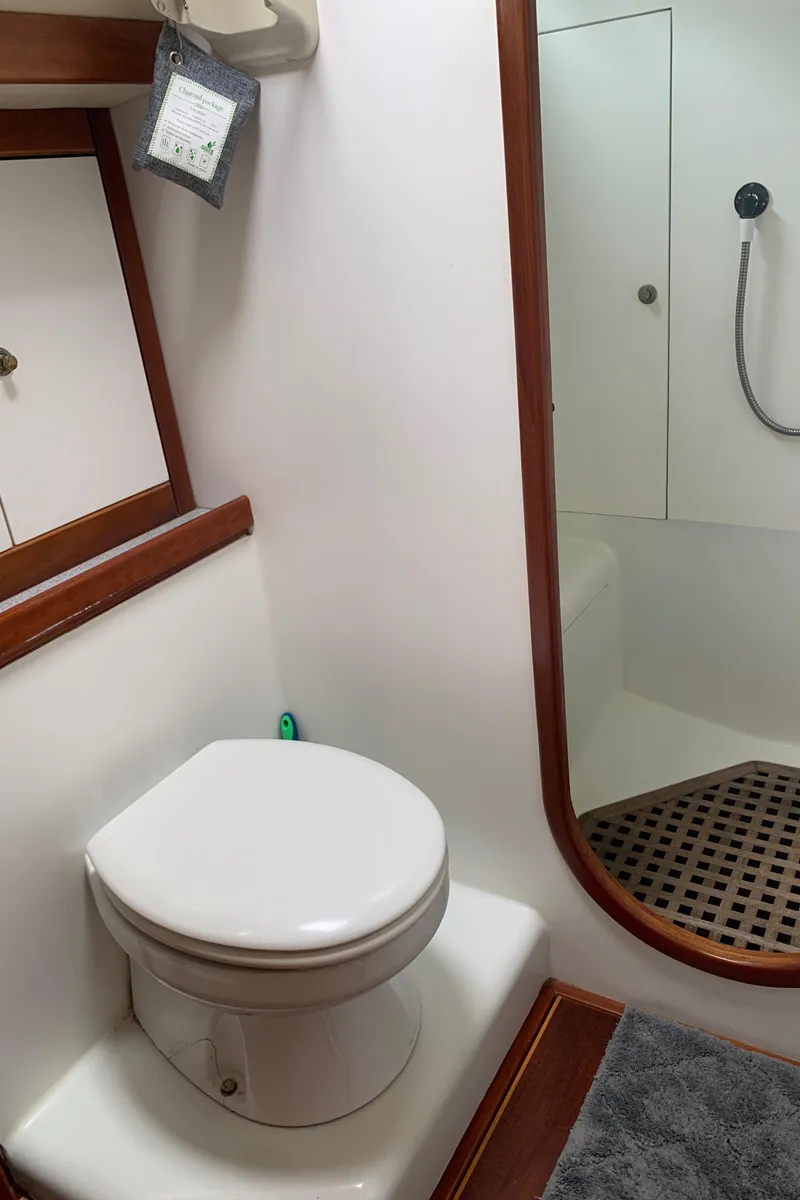 Slide: The Image of 2004 ShearWater 45 yacht bathroom with toilet, shower, and wooden accents. - 12