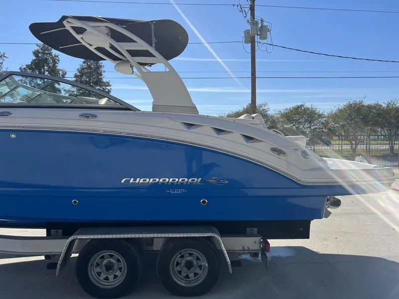 Slide: The Image of 2018 Chaparral 244 Sunesta Xtreme boat on trailer, blue and white design, sunny day. - 9