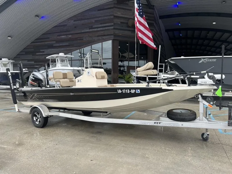 Slide: The Image of 2023 Xpress H20 BAY boat on trailer, displayed outside dealership with American flag. - 1