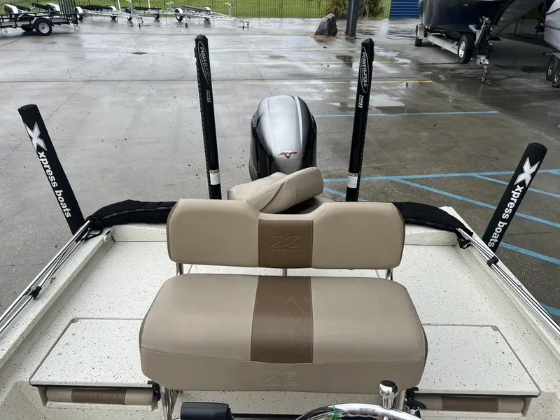 Slide: The Image of 2023 Xpress H20 BAY boat with beige seating and motor, parked on wet pavement. - 10