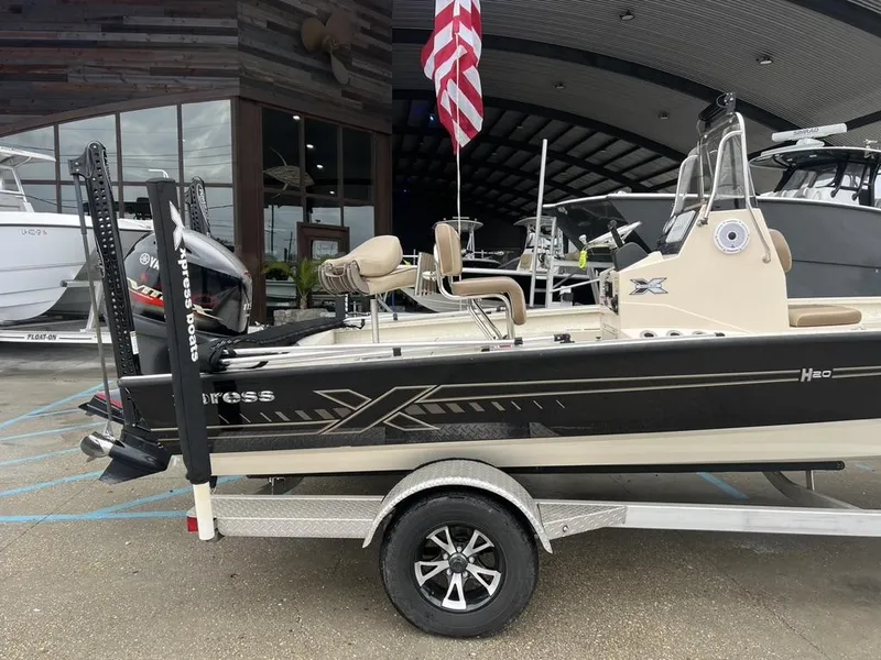 Slide: The Image of 2023 Xpress H20 BAY boat on trailer, displayed outdoors with American flag. - 2