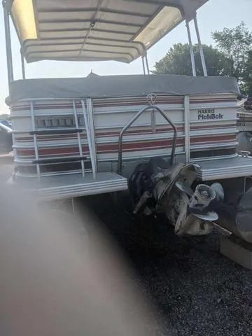 Slide: The Image of 1992 Harris 280 Heritage pontoon boat with canopy and outboard motor, parked on gravel. - 5