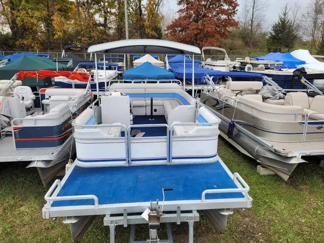 Slide: The Image of 1992 Harris Sunliner pontoon boat with blue and white seating, parked among other boats. - 11