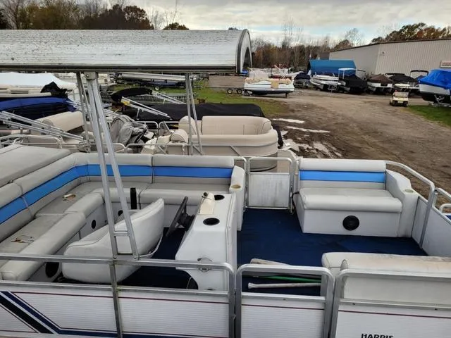 Slide: The Image of 1992 Harris Sunliner pontoon boat with blue and white seating, parked outdoors. - 13