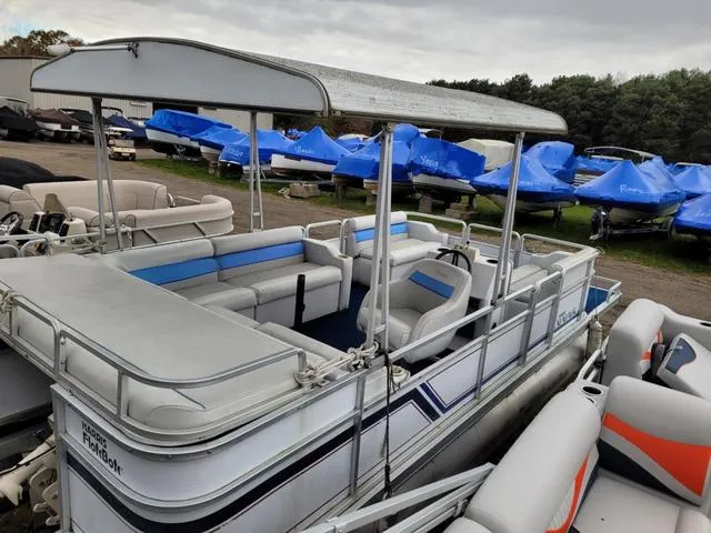 Slide: The Image of 1992 Harris Sunliner pontoon boat with canopy, parked among other boats in a storage area. - 14
