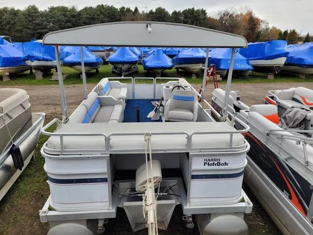 Slide: The Image of 1992 Harris Sunliner pontoon boat with canopy, docked among other boats, outdoor setting. - 15