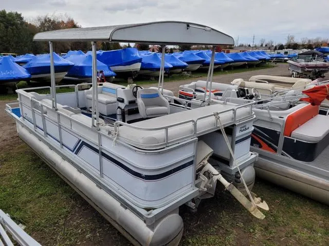 Slide: The Image of 1992 Harris Sunliner pontoon boat with canopy, parked among other boats in a storage area. - 16