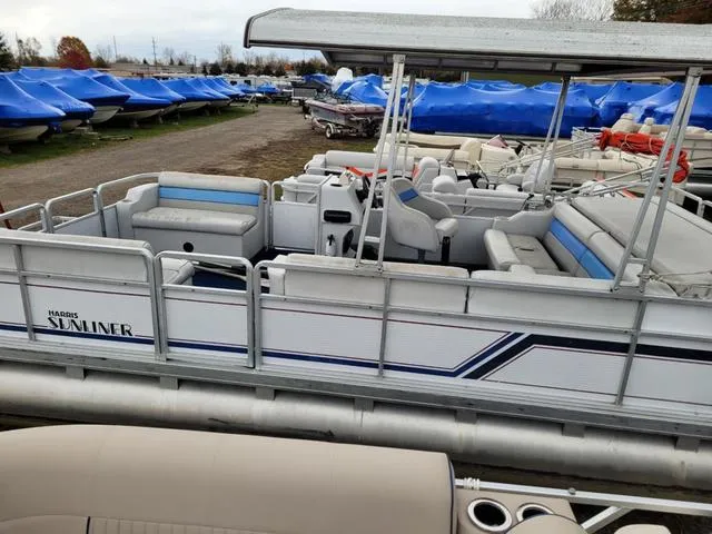 Slide: The Image of 1992 Harris Sunliner pontoon boat with seating, docked among covered boats. - 17